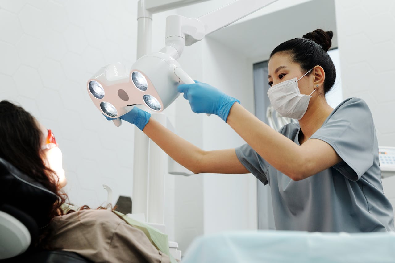 Dentist in a dental clinic adjusting overhead light for patient. Modern healthcare setting.